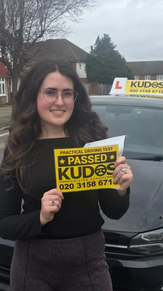 Student holding his licence next to the Kudos Driving School car